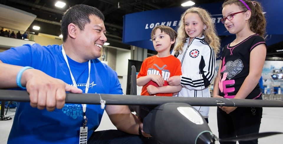 Volunteer from Lockheed Martin seen with three young children